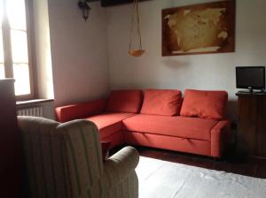 sala de estar con sofá rojo y silla en Casale La Selva Cottege grande, en Piano Porlezza