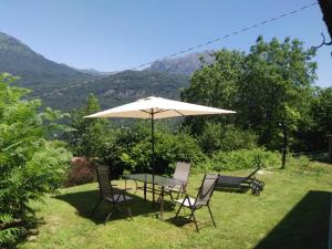 een tafel en stoelen met een parasol in het gras bij Casale La Selva Cottege grande in Piano Porlezza