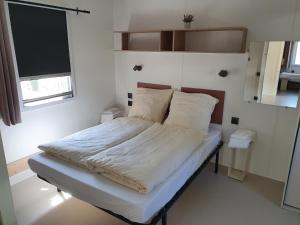 un letto con lenzuola e cuscini bianchi in una stanza di Ferienpark Auf dem Simpel - Heide-Lodge barrierefrei a Soltau