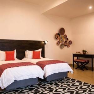 a bedroom with two beds with red and white sheets at Tabokana House in Victoria Falls