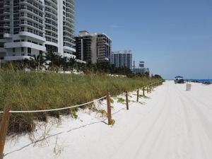 uma praia arenosa com uma cerca e alguns edifícios altos em 2 bedroom apartment w balcony & ocean view @ the beach 154 em Miami Beach