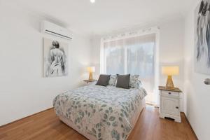 a white bedroom with a bed and a window at Magnolia Sea Views in Mandurah