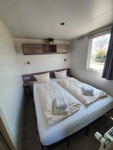 ein großes weißes Bett in einem Zimmer mit Fenster in der Unterkunft Ferienpark Auf dem Simpel - Mobilheim 1 in Soltau