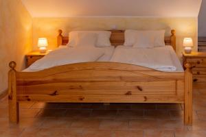 ein großes Holzbett mit zwei weißen Kissen und zwei Lampen in der Unterkunft Ferienpark Auf dem Simpel - Dreibettzimmer in Soltau