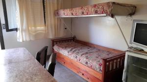 Dormitorio pequeño con litera y mesa en Complejo Las Toninas en Las Toninas