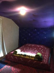 Ce lit se trouve dans un dortoir doté d'un plafond violet. dans l'établissement ATFIL CAMP, à M'Hamid El Ghizlane