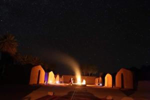- une vue nocturne sur un désert avec un feu au milieu dans l'établissement ATFIL CAMP, à M'Hamid El Ghizlane