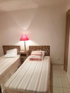 two beds in a room with a lamp on a table at L'Olivier - Centre village - Au calme in Bessan