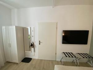 une chambre blanche avec deux chaises et une télévision murale dans l'établissement Studio 229, à Dortmund