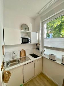 uma cozinha branca com um lavatório e uma janela em Studio 229 em Dortmund