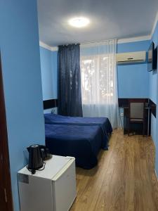 Dormitorio azul con cama, mesa y silla en Autopapa en Rustavi
