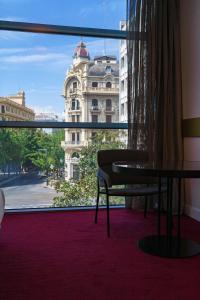 um quarto com uma mesa e vista para um edifício em Hotel Colón Centro em Granada