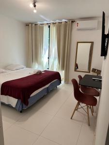 1 dormitorio con cama, escritorio y espejo en Suite Real Residencial, en Río de Janeiro