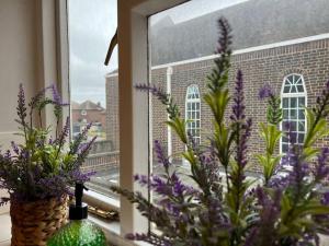una ventana con flores púrpuras y un jarrón en el alféizar de la ventana en Central Welling Flat en Welling