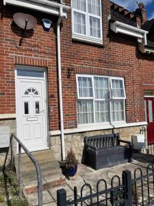a brick house with a white door and a bench at Cosy Stay in the Heart of Dover in Kent