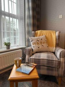 ein Wohnzimmer mit einem Stuhl und einem Tisch mit einem Buch in der Unterkunft Cosy Stay in the Heart of Dover in Kent