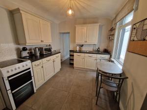 a kitchen with white cabinets and a table in it at 4 Bedroom house in Merthyr Tydfil. Near Brecon Beacons National Park in Dowlais