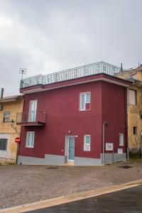 een rood gebouw met een balkon erboven bij ARTEMIDE "Corte Segreta" B&B SUITE SPA in San Cipriano Picentino