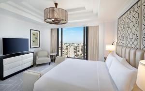 une chambre avec un lit blanc et une grande fenêtre dans l'établissement The St. Regis Amman, à Amman