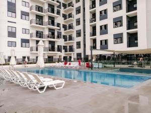 a swimming pool with lounge chairs and a building at Nasma Luxury Stays - Home-Style 2BR Apartment with a Balcony View in Dubai