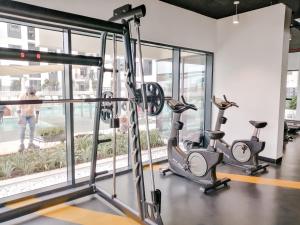 a gym with treadmills and ellipticals in front of a window at Nasma Luxury Stays - Home-Style 2BR Apartment with a Balcony View in Dubai