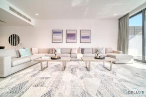 Luxury 4BR Villa with Assistant’s Room Al Dana Island, Fujairah by Deluxe Holiday Homes في الفجيرة: غرفة معيشة مع أريكة وطاولتين