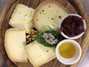 une assiette de fromage et d’autres denrées alimentaires sur une table dans l'établissement Rifugio Vieux Crest, à Champoluc