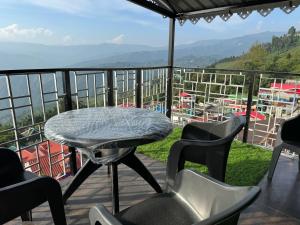 a table and chairs on a balcony with a view at Aama Home Stay in Kurseong