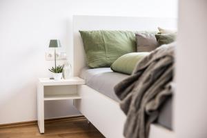 a white couch with a green pillow and a night stand at Smart Living Dornbirn in Dornbirn