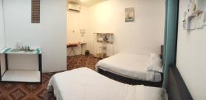 Cette petite chambre comprend deux lits et une table. dans l'établissement Bulat Cottage, à Pantai Cenang