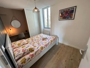 a bedroom with a bed with a comforter and a window at Appartement JAZZ Vienne nord in Vienne