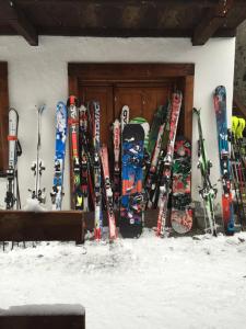 Un tas de skis et de snowboards sont bordés d'un mur. dans l'établissement Rifugio Vieux Crest, à Champoluc