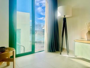 um quarto com um candeeiro de chão e uma grande janela em Canaryislandshost l Cala em Punta Mujeres