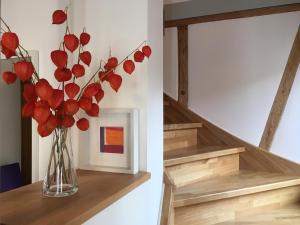 un vase avec des fleurs rouges assis sur un escalier dans l'établissement Ferienhaus "Am Saarbach", à Ochsenfurt