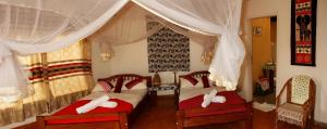 1 dormitorio con 2 camas y almohadas rojas y blancas en Euphorbia Safari Lodge, en Kasenyi