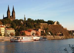 a white boat on the water near a city at SPA SPA Apartments Vyšehrad in Prague