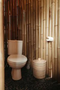 uma casa de banho com WC e uma parede de bambu em The Nude House em Selat
