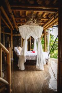 een slaapkamer met een hemelbed en witte gordijnen bij The Nude House in Selat