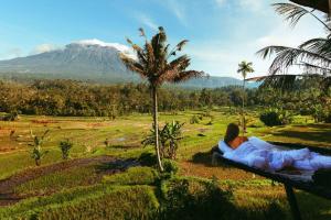 Een man op een bank die naar een berg kijkt. bij The Nude House in Selat