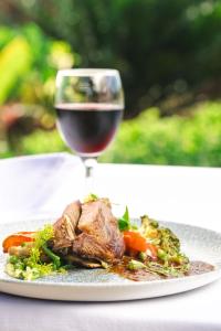 a plate of meat and vegetables with a glass of wine at Zanzibar Queen Hotel in Matemwe