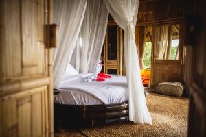 um quarto com uma cama de dossel com flores vermelhas em The Nude House em Selat