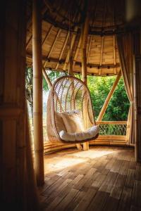 een rieten stoel op de veranda van een prieel bij The Nude House in Selat