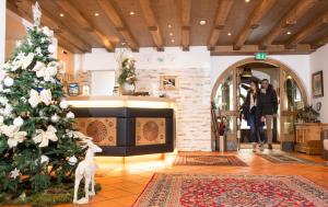 Un árbol de Navidad en una habitación con una mujer tomando una foto en Bergsporthotel Antonie, en Gries im Sellrain