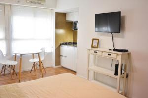 Una sala de estar con un televisor y una mesa con sillas. en Studio Congreso, en Buenos Aires