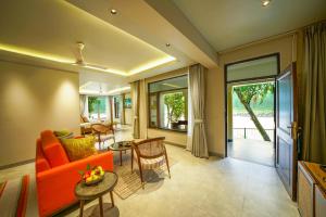 a living room with an orange couch and a table at Anand Kashi by the Ganges Rishikesh - IHCL Seleqtions in Rishīkesh