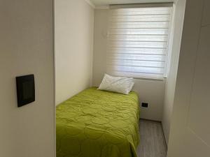 ein kleines Schlafzimmer mit einem grünen Bett und einem Fenster in der Unterkunft Departamento La Serena in La Serena