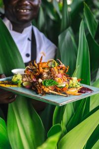a man holding a plate of food with crabs on it at Zanzibar Queen Hotel in Matemwe