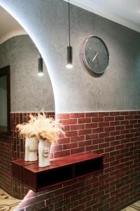 una pared de ladrillo con un reloj y dos jarrones en un estante en Gallery Elit Hotel en Dunaivtsi