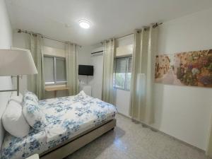 een slaapkamer met een bed met blauwe en witte kussens bij Amigo Hotel On The Beach in Nahariyya