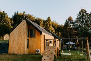 a wooden cabin with a slide and a playground at Domki pod Kamionna in Laskowa